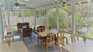 Un patio cubierto con una mesa y sillas de madera, un sofá y un ventilador de techo.