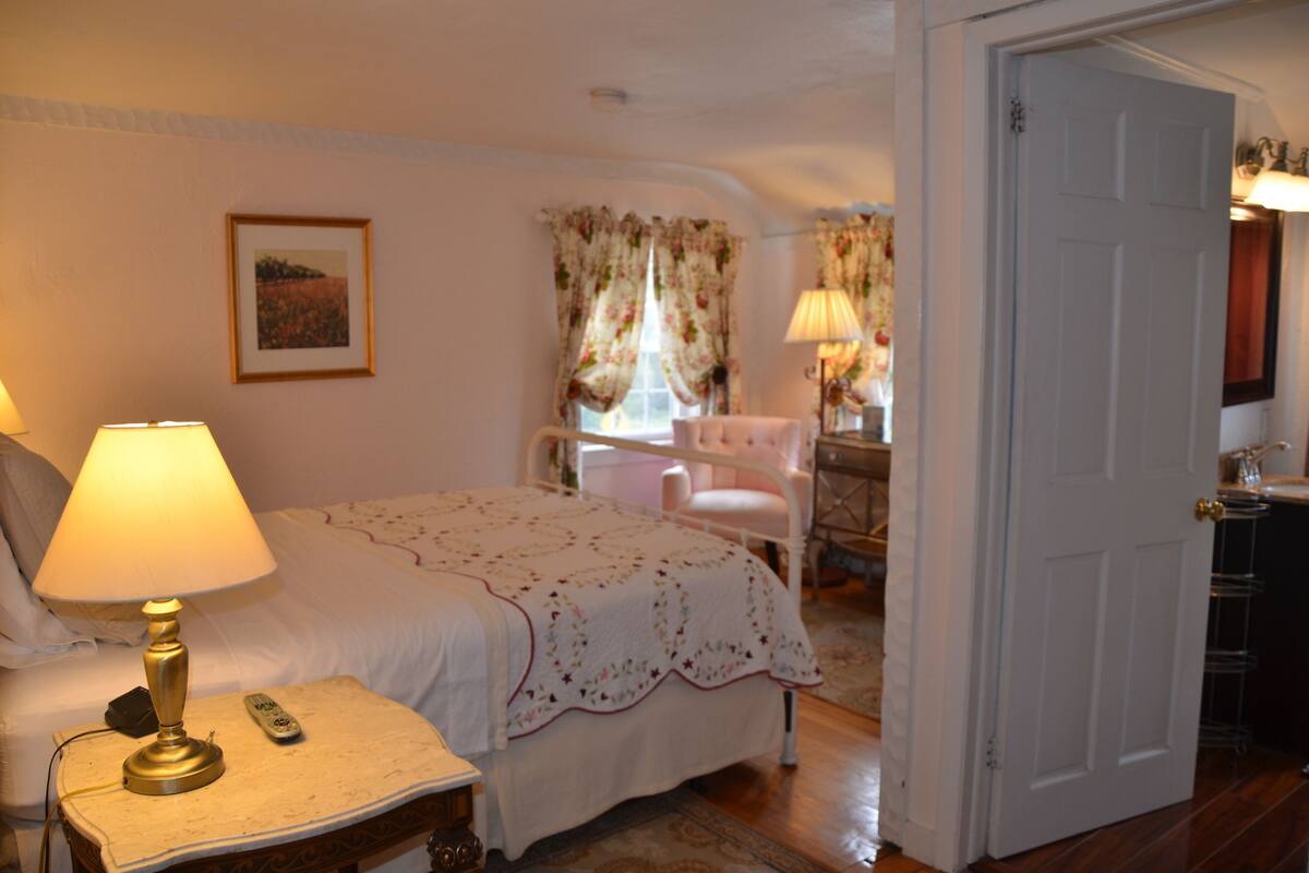 A bedroom with a bed, bedside lamp, and a chair.