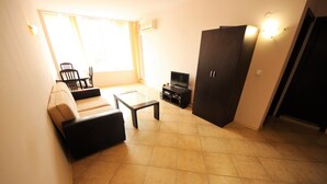 Una sala de estar con un sofá, una mesa de centro, un televisor y un armario.