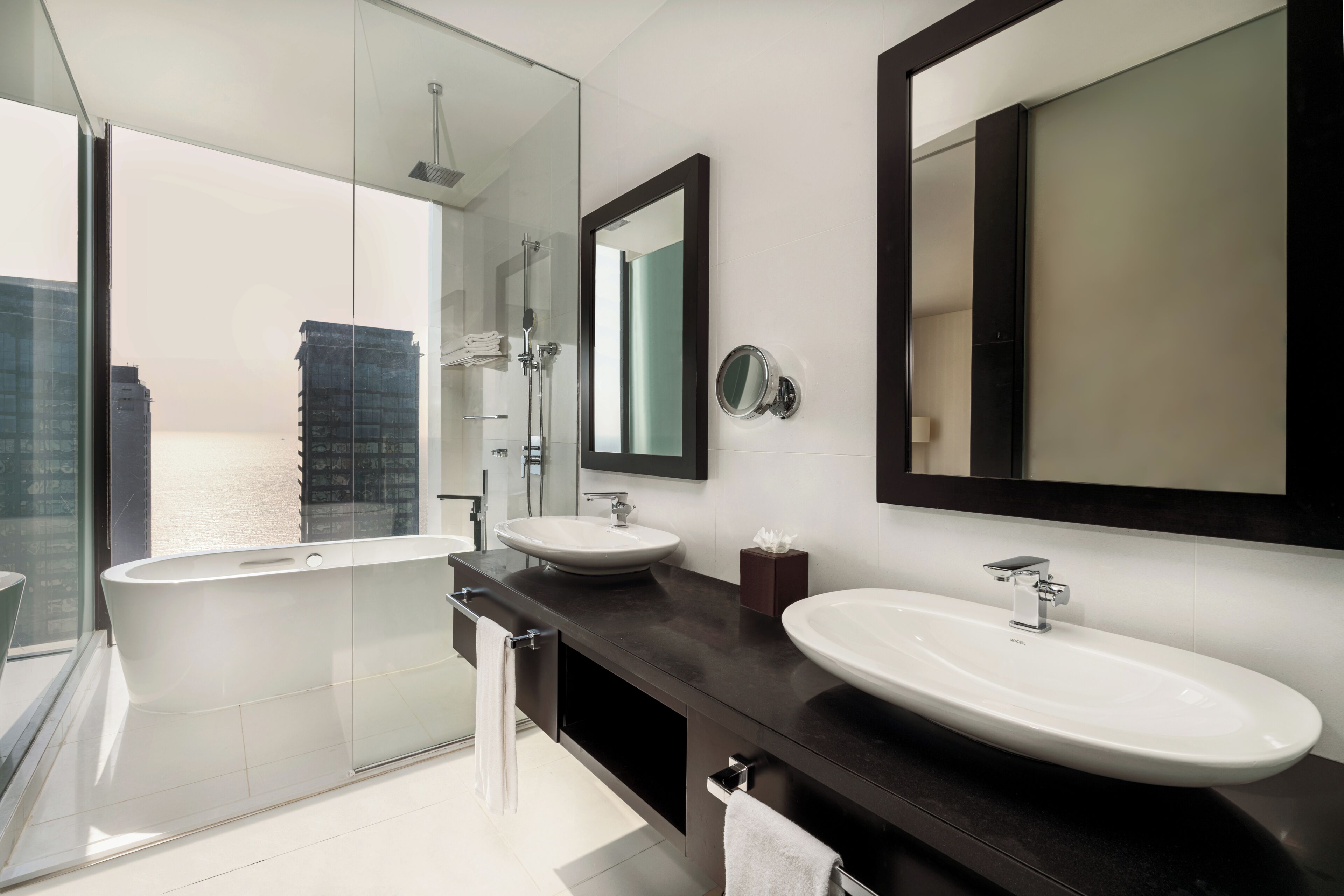 A modern bathroom with a glass-enclosed shower, two sinks, and a large mirror.