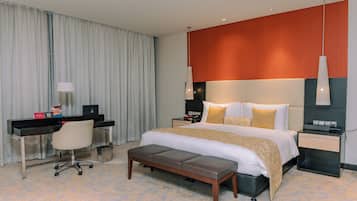 A hotel room with a bed, desk, chair, and a small bench.
