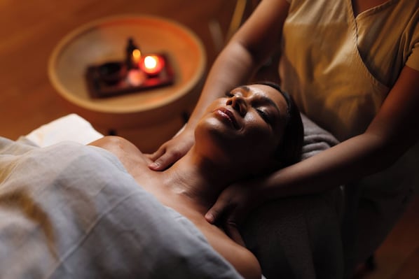 A person lying on a bed in a room with a small table and a candle in the background. - Pullman Colombo City Centre (Colombo)