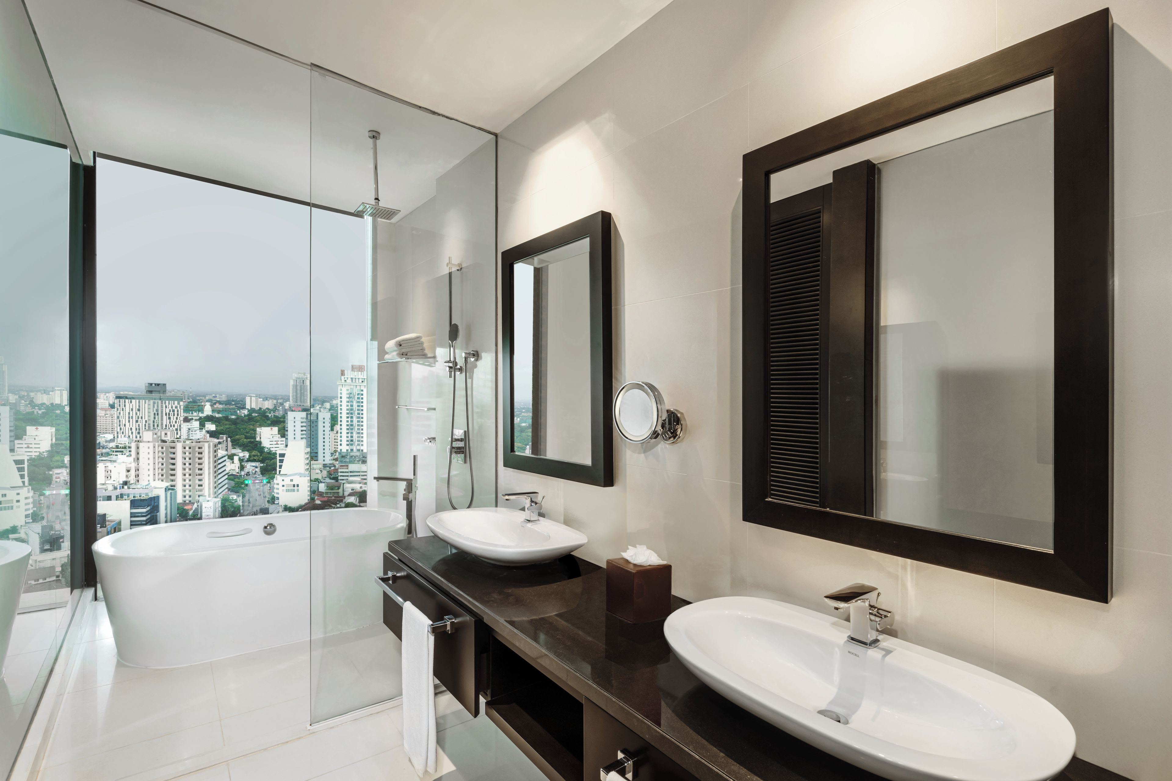 Un baño moderno con bañera, dos lavamanos y un espejo grande.