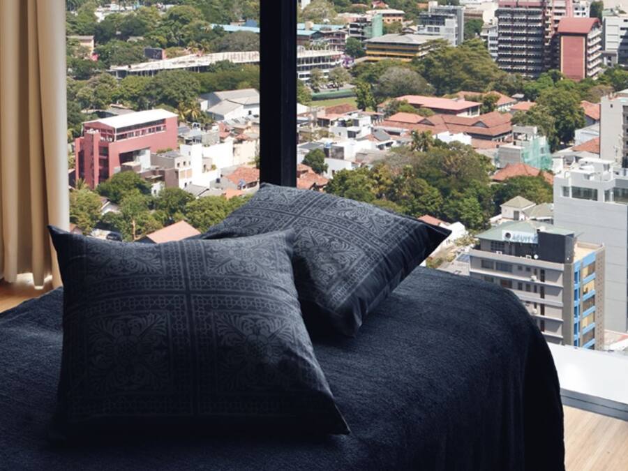 Un dormitorio moderno con vistas a la ciudad, un armario de madera y una mesita de noche con toallas.