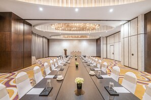 Una sala conferenze con un lungo tavolo, sedie e un lampadario.