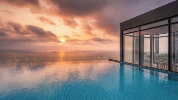 Une piscine à débordement offrant une vue imprenable sur le coucher de soleil sur l’océan.