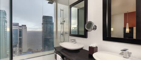 A modern bathroom with a large glass shower, a white sink, and a large mirror.