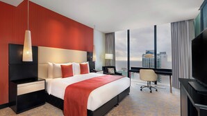 A hotel room with a large bed, a desk, a chair, a TV, and a view of the cityscape. - Pullman Colombo City Centre (Colombo)