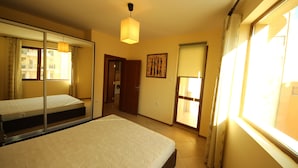 A bedroom with a bed, a mirror, a door, and a window. - Menada Amadeus 3 Apartments (Sunny Beach)