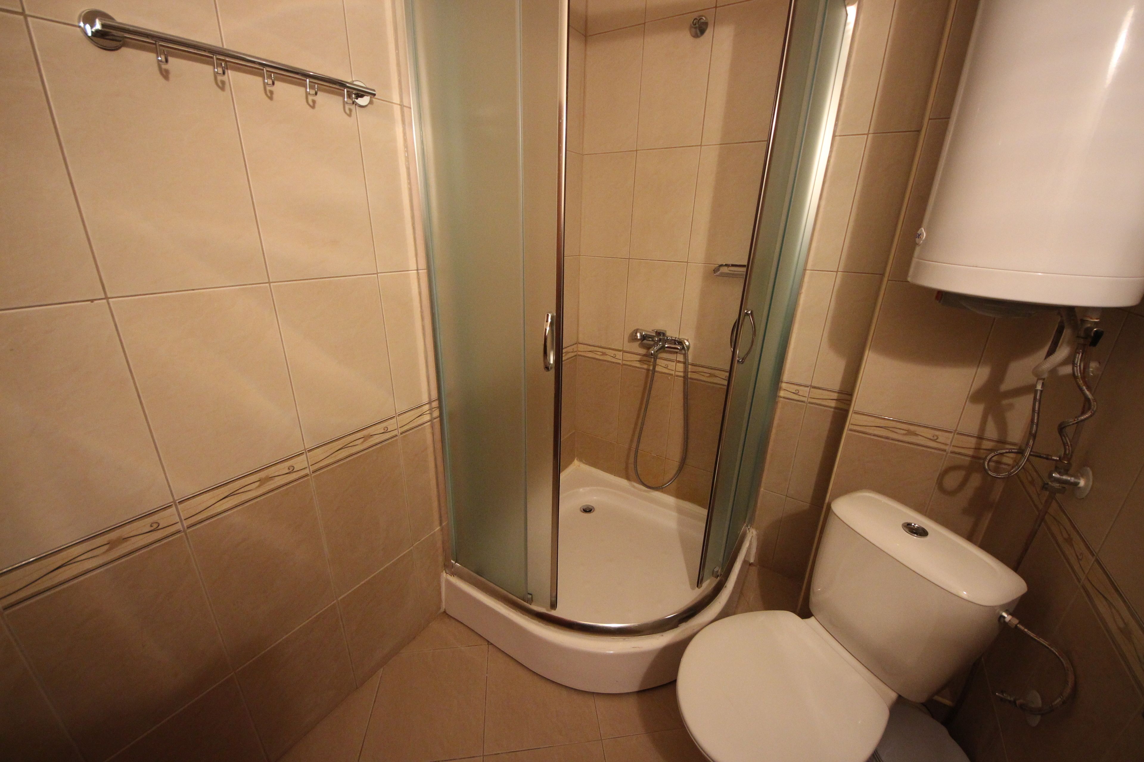 A bathroom with a glass-enclosed shower, a toilet, and a towel rack.