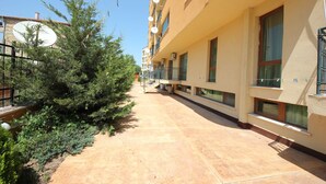 A building with multiple balconies and windows, a paved walkway, and some greenery. - Menada Amadeus 3 Apartments (Sunny Beach)
