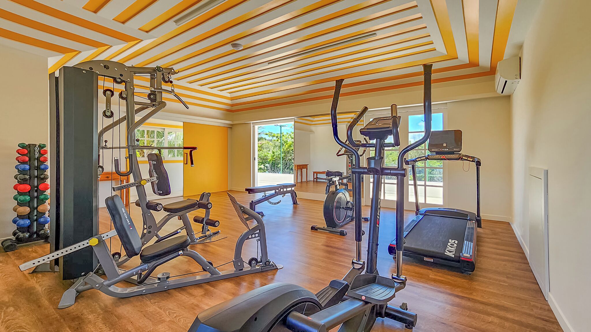 A spacious home gym with various exercise equipment, including a treadmill, elliptical, and weight machine.