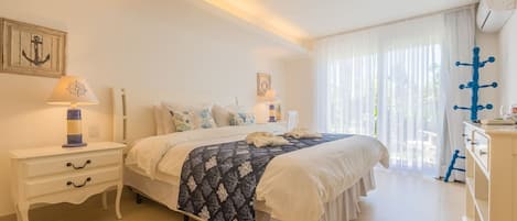 A bedroom with a bed, a nightstand, a dresser, and a window with curtains.