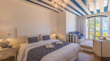 Une chambre à coucher comprenant un lit, des tables de chevet, une commode, un bureau, une chaise et une fenêtre avec des rideaux.