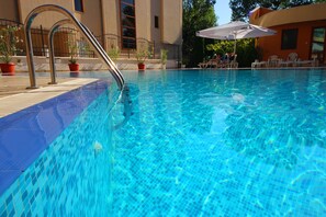 Una piscina al aire libre de temporada, sombrillas, tumbonas