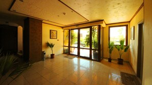 A spacious lobby with a tiled floor, large glass doors leading outside, and several potted plants. - Menada Amadeusz 1 Apartments (Sunny Beach)