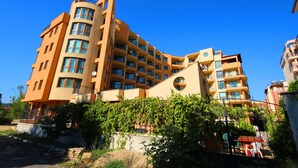 A multi-story hotel with balconies and a circular window on the facade. - Menada Amadeusz 1 Apartments (Sunny Beach)
