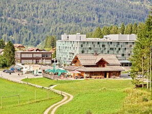 Un pueblo de montaña con una mezcla de edificios modernos y tradicionales, una carretera despejada y un paisaje verde.
