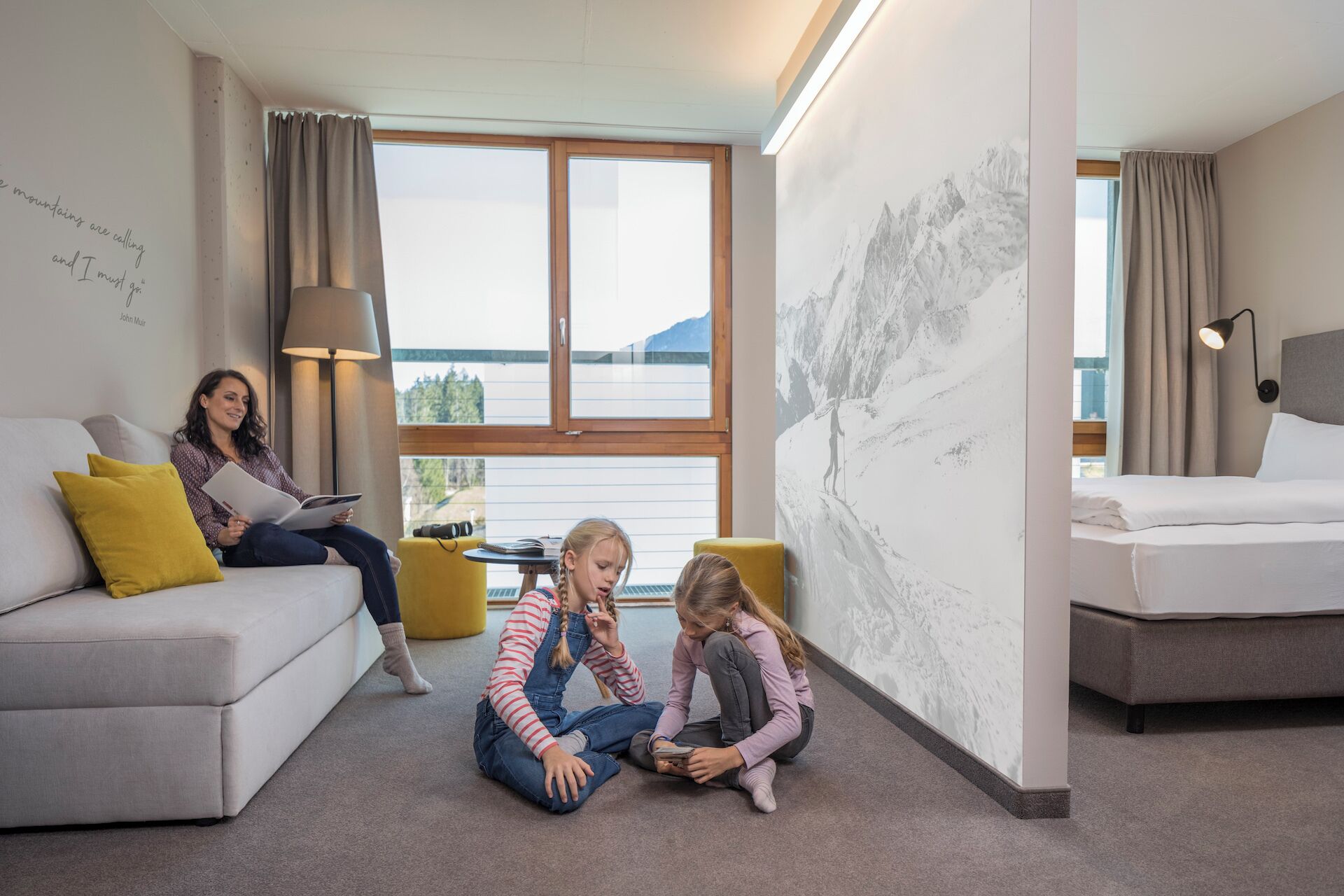 Ein modernes Wohnzimmer mit einer Couch, einem Esstisch und einem großen Fenster mit Bergblick.