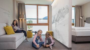 Ein modernes Wohnzimmer mit einer Couch, einem Esstisch und einem großen Fenster mit Bergblick.