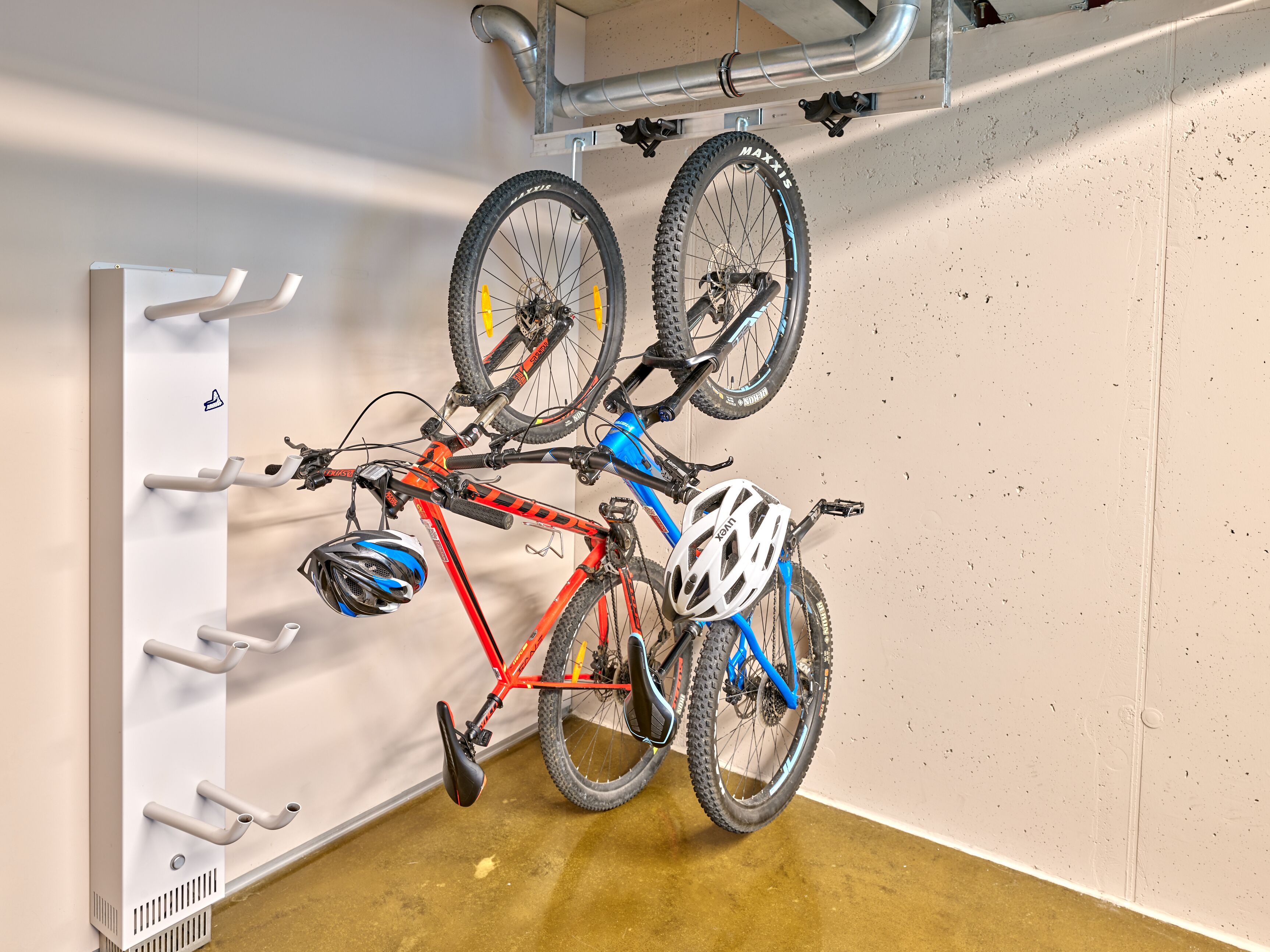 A bicycle mounted on a wall-mounted rack with a metal pipe structure above.
