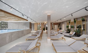 Un área de piscina interior moderna con sillones de descanso y vistas a la piscina.