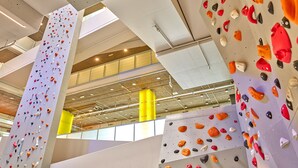 Eine Kletterhalle mit mehreren Kletterwänden, Deckenleuchten und sichtbaren Stahlträgern.