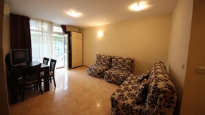 A living room with a sofa, a TV, and a dining table with chairs. - Menada Elit IV Apartments (Sunny Beach)