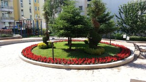 A landscaped garden with a circular flower bed, a playground, and a bench. - Menada Elit IV Apartments (Sunny Beach)