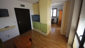 A compact kitchen with a black door, a small dining area, and a view of a hallway. - Menada Amara Apartments (Sunny Beach)
