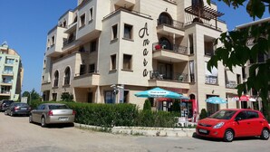A multi-story building with balconies, a supermarket, and a Coca-Cola sign. - Menada Amara Apartments (Sunny Beach)