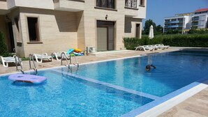 A swimming pool with a lifeguard chair, lounge chairs, and a pool ladder. - Menada Amara Apartments (Sunny Beach)
