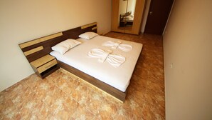 A neatly made bed with towels, a wooden headboard, a wooden nightstand, and a large mirror.