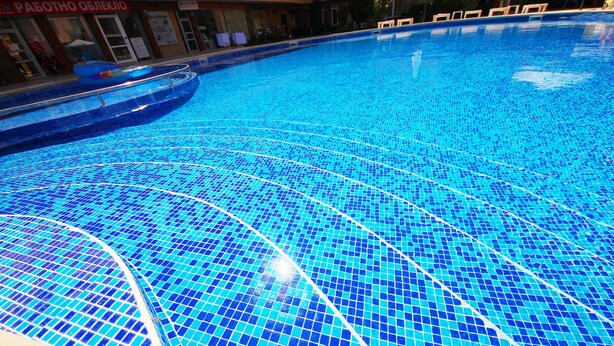 A large indoor swimming pool with blue mosaic tiles.
