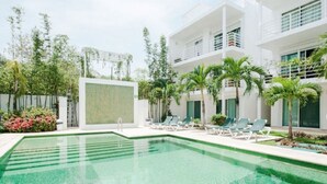 A modern hotel with a swimming pool, lounge chairs, and palm trees. - Pelicanos 112 (Playa del Carmen)
