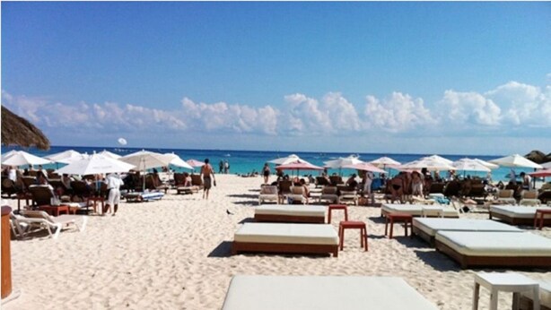 A beach with sun loungers and umbrellas, a sandy beach, and the ocean in the background. - Pelicanos 112 (Playa del Carmen)