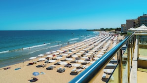 A beach with rows of sunbeds and umbrellas, a clear sky, and a view of the sea. - MPM Hotel Arsena (Nessebar)