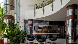 A modern lobby with a reception desk, seating area, and potted plants. - MPM Hotel Arsena (Nessebar)