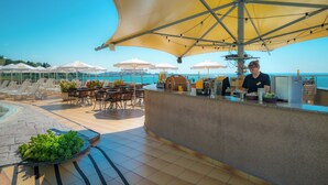 A poolside bar area with outdoor seating and umbrellas, overlooking a body of water. - MPM Hotel Arsena (Nessebar)