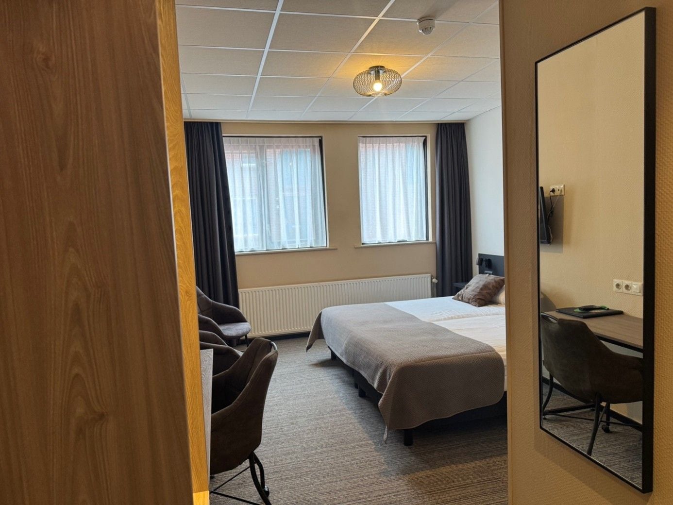 Una habitación de hotel con cama, escritorio, silla y televisión.