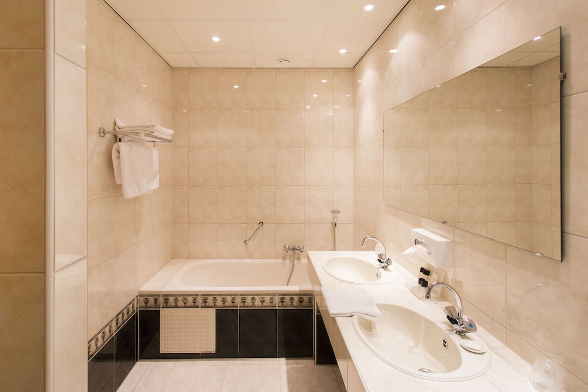 A modern bathroom with a bathtub, two sinks, and a large mirror.