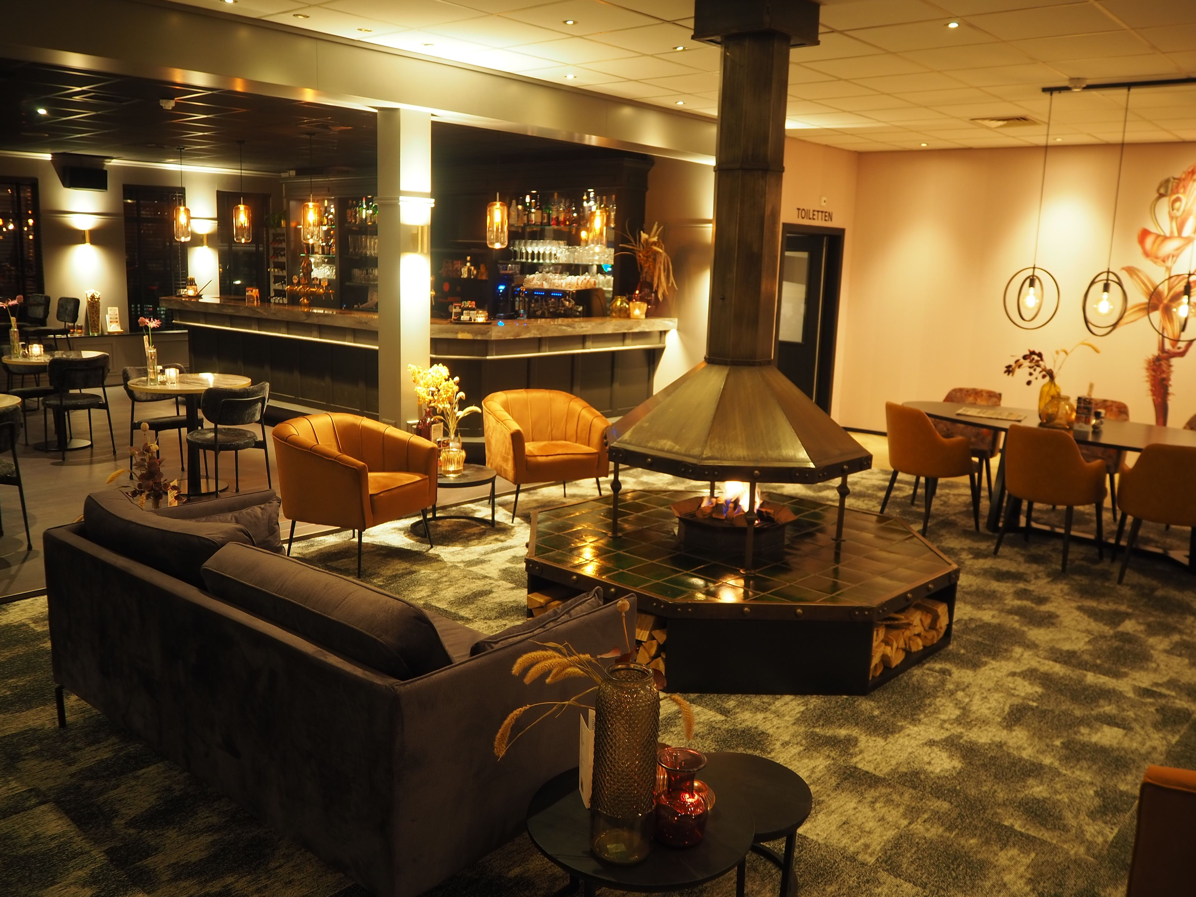 Ein gemütlicher Lounge-Bereich mit Sofas, einem Kamin und einer Bar im Hintergrund.
