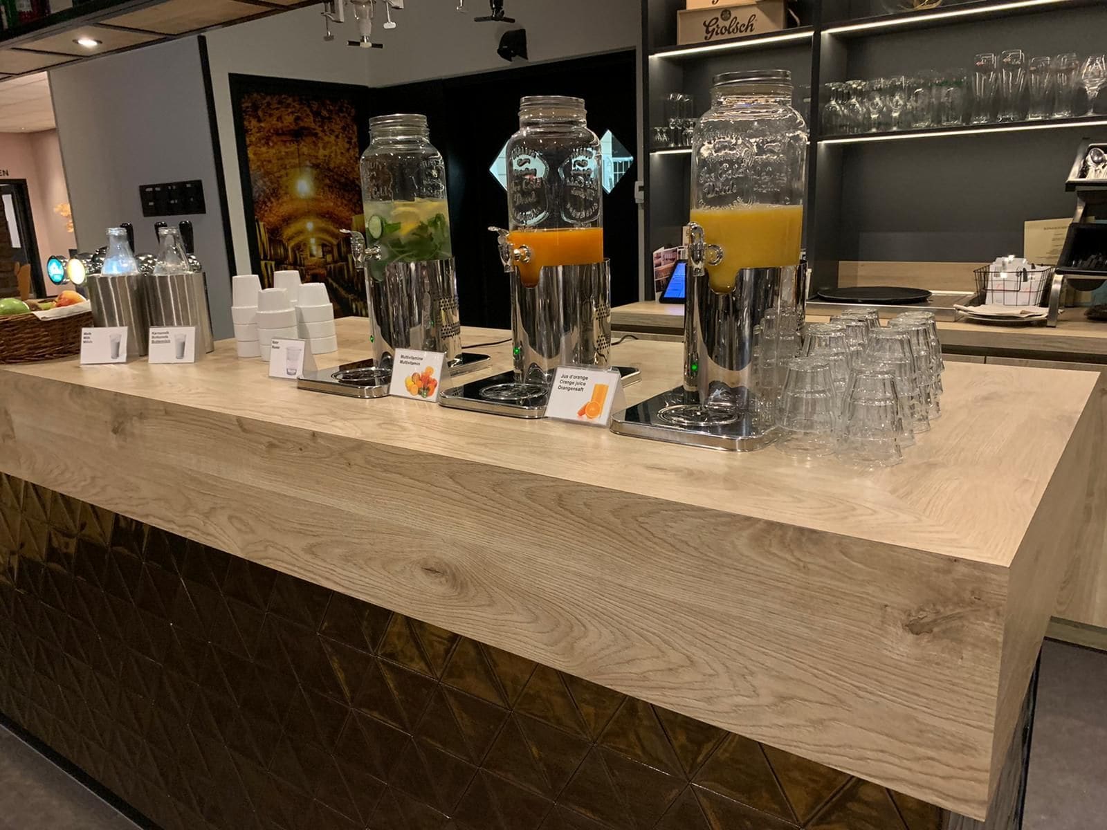 A bar area with multiple drink dispensers and a selection of glasses.