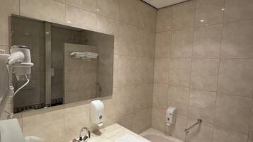 Un baño moderno con lavamanos, espejo, secador de pelo y bañera.