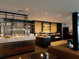Un moderno vestíbulo de hotel con recepción, área de descanso y bufé.