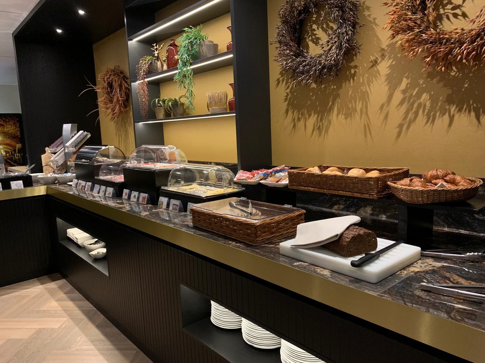 A buffet area with various food items, including bread, pastries, and a cake.