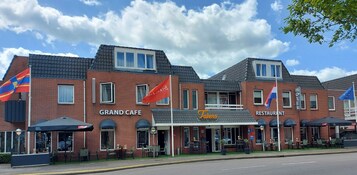 Un edificio de ladrillo con un cartel que indica 'Grand Cafe' y 'Talens Restaurant' en la planta baja.