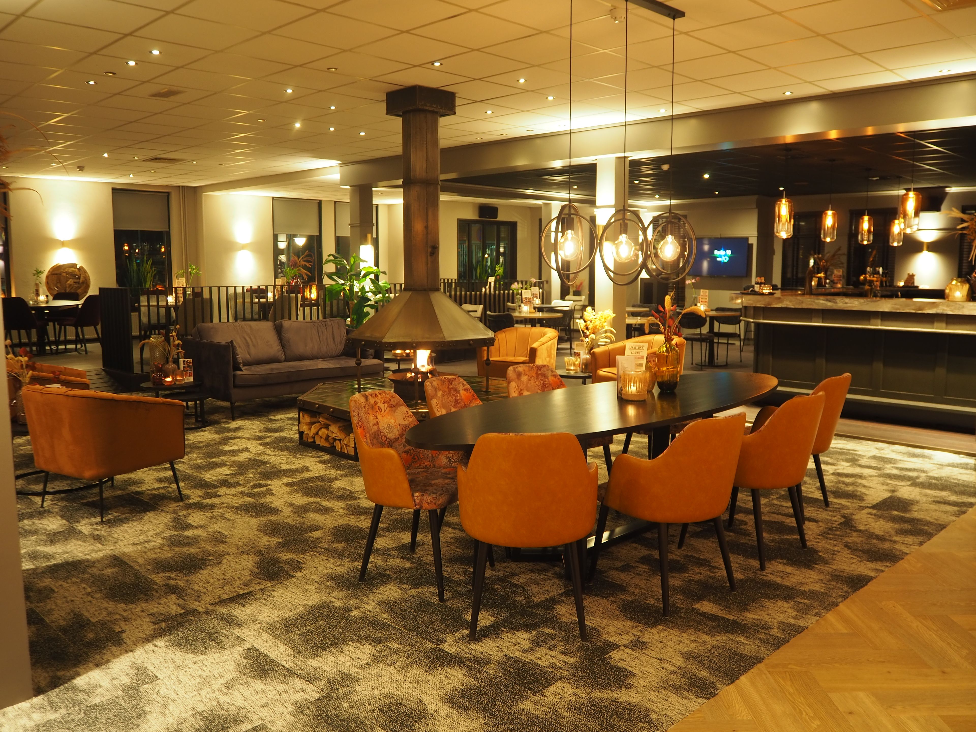 Un hall d’hôtel moderne avec un espace salon central, un bar et une cheminée.