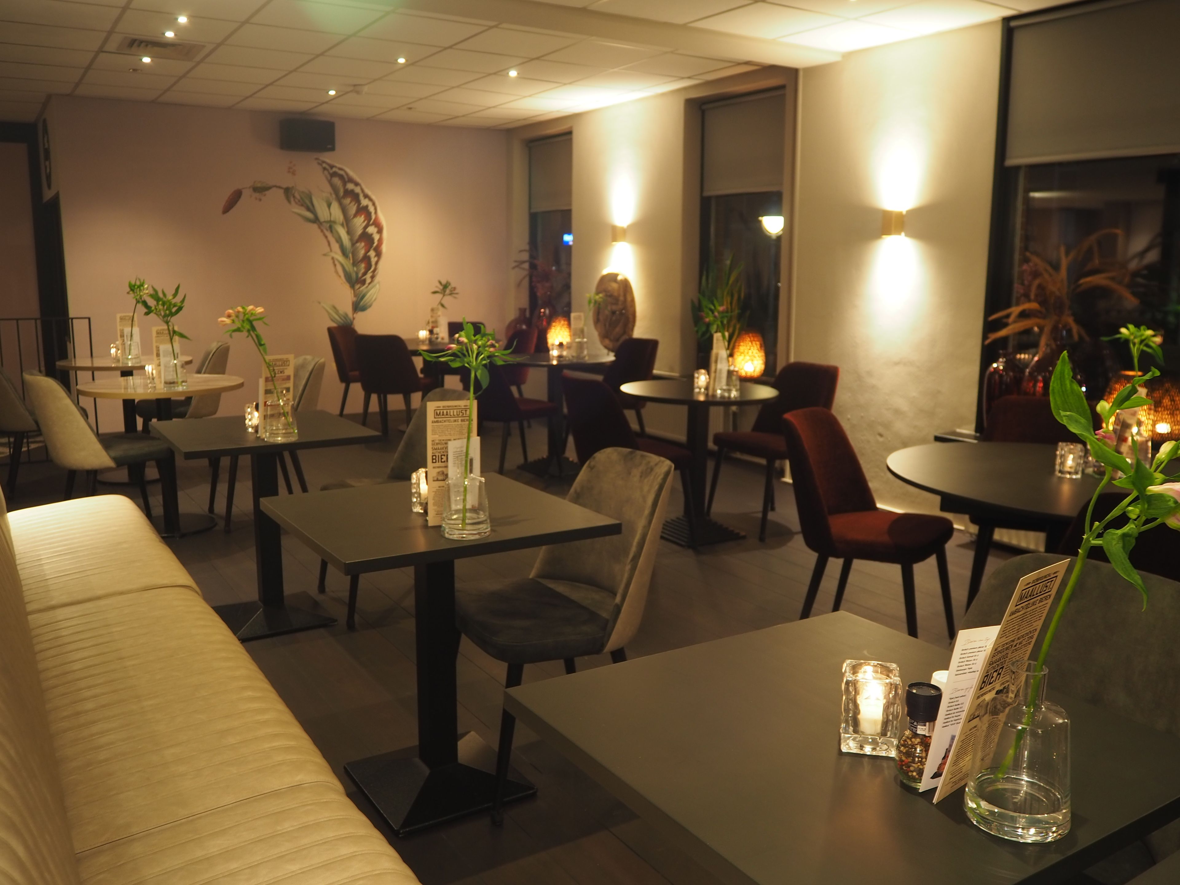 Interior de restaurante con mesas, sillas y ambiente iluminado con velas.