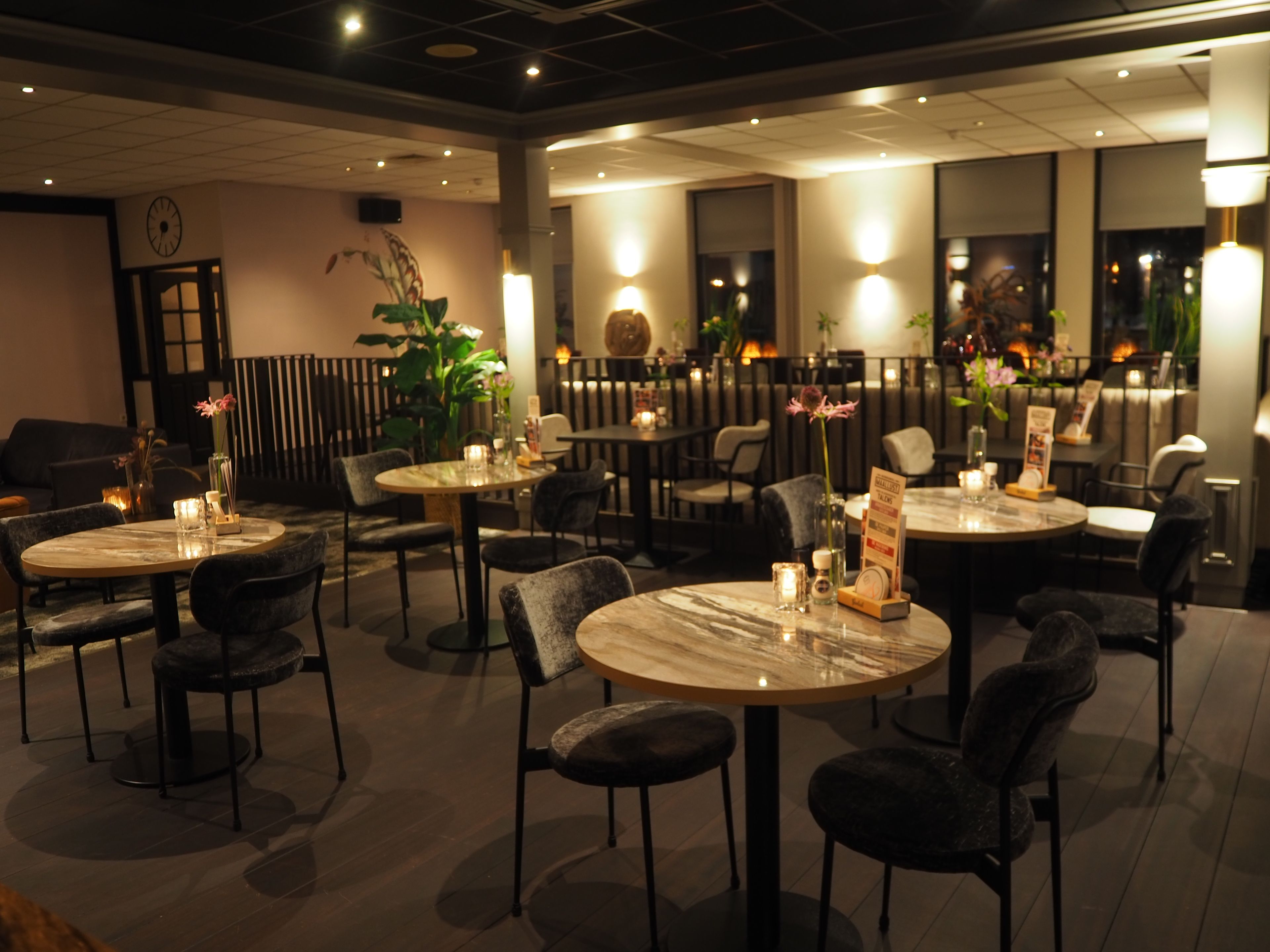 L’intérieur d’un restaurant, avec des tables rondes, des chaises et un éclairage d’ambiance.